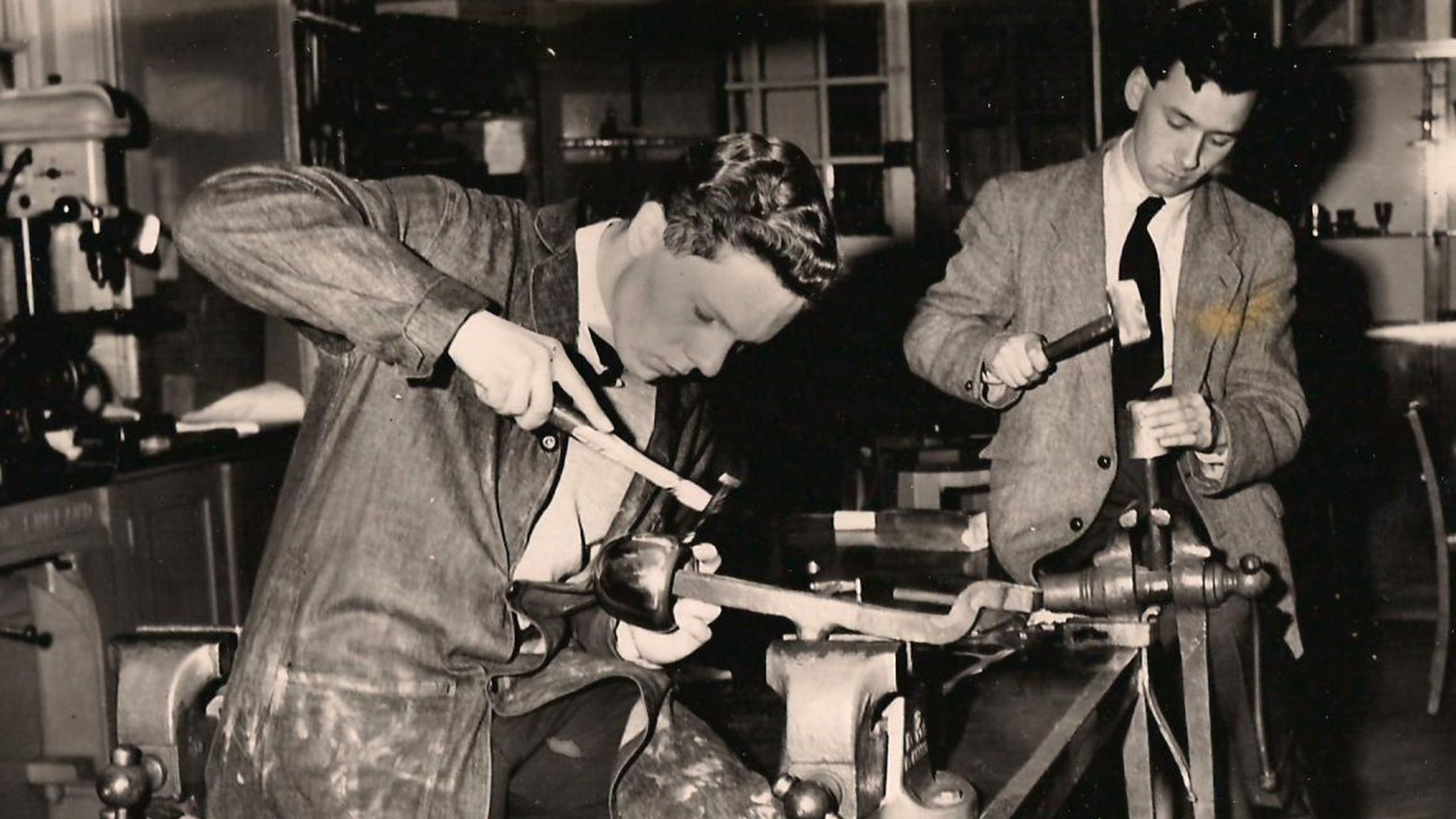 Image: two men shape products with hammers