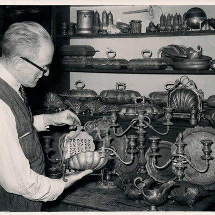 Image: Harold Evans looking at silver products