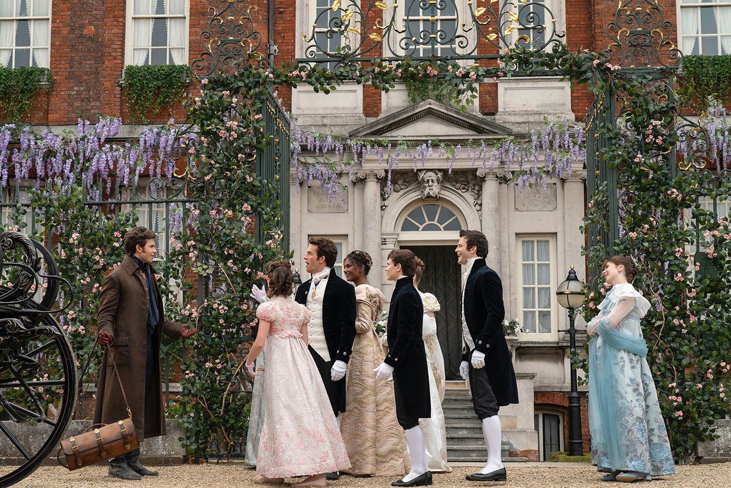 The cast of Bridgerton stand outside Ranger's House and greet Colin, returning from his Grand Tour in a long brown overcoat.