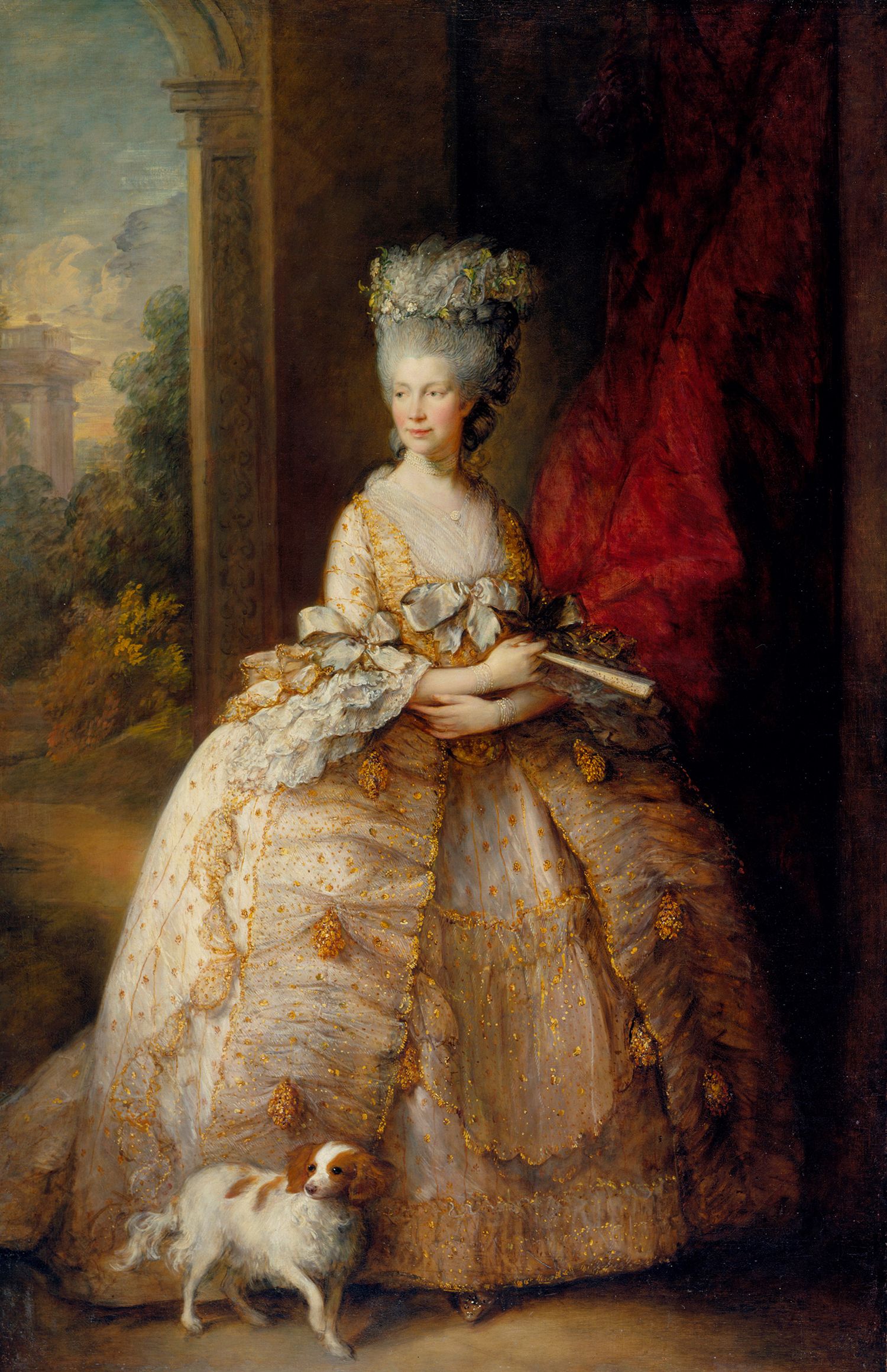 A portrait of Queen Charlotte by Thomas Gainsborough. The queen wears a lavish gold, white and yellow dress, with a bow at the centre, and frills over her elbows. She has grey hair worn up in an ornate hairdo. There's a brown and white dog at her feet.