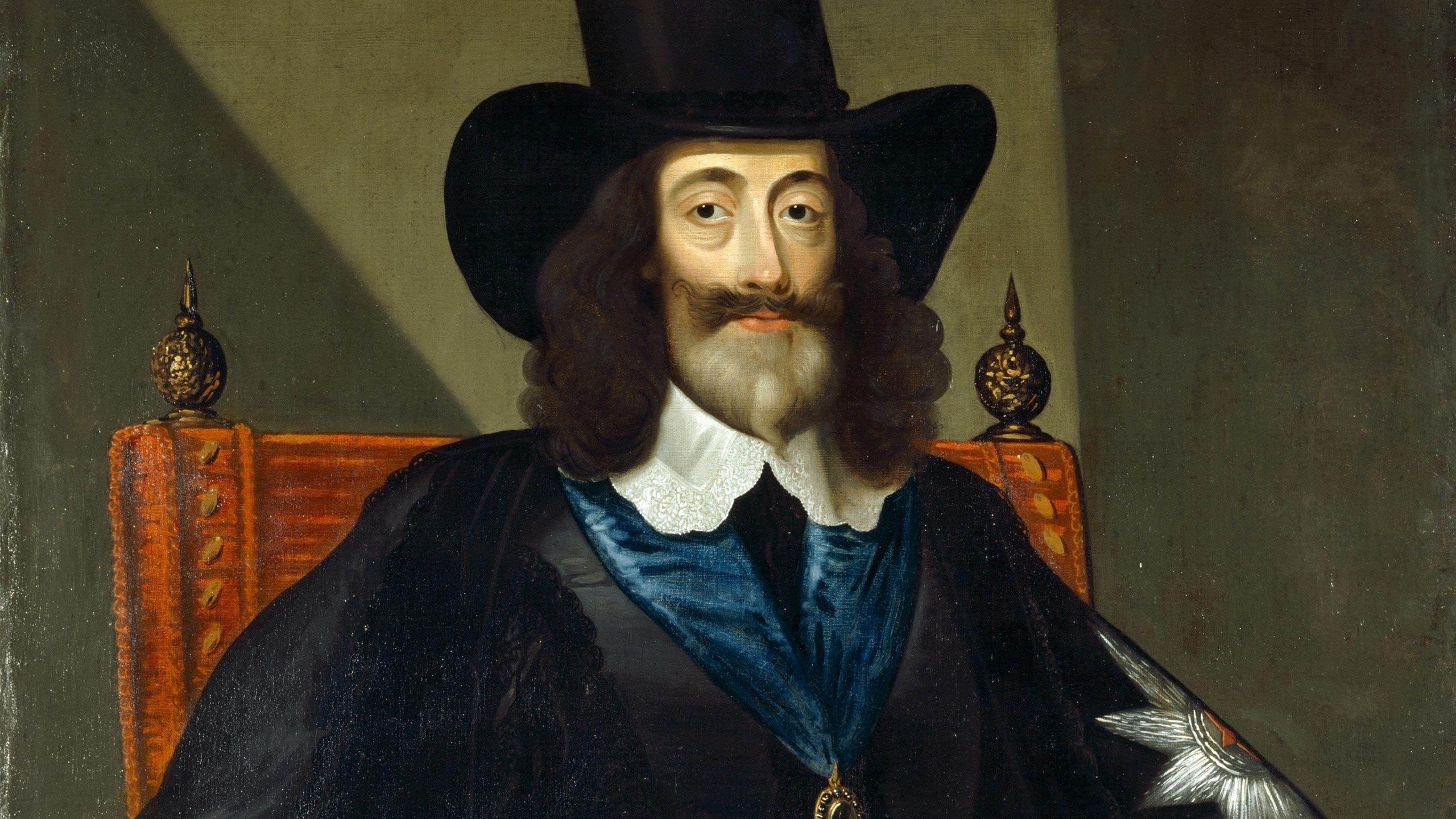Oil painting of Charles I, seated on a red-upholstered chair, holding a slip of paper in one hand and a staff in the other.